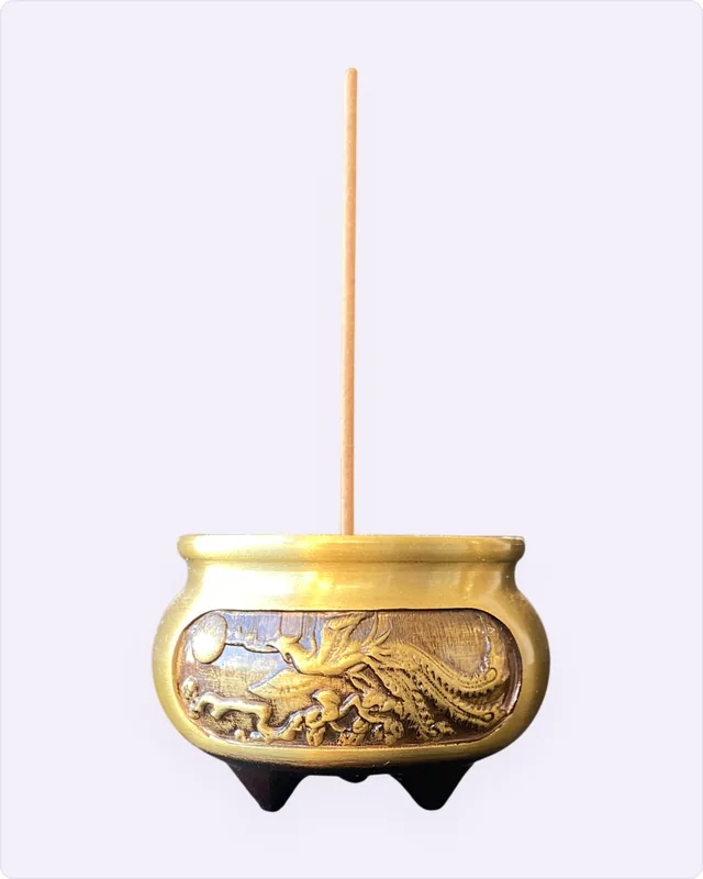 黃銅三足香爐,爐身有鳳凰浮雕,爐中插著一支香。